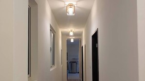 A narrow, well-lit hallway with wooden flooring and white walls, leading to a room with a visible door and a small window. - Full 2B2B Accessible Home on the 1st Floor, Sleeps 5, in Xinyi District, Taipei. (Taipei City)