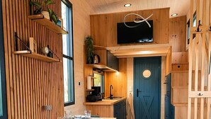 Eine moderne Küche mit Holzschränken, ein Essbereich mit Tisch für vier Personen und eine blaue Tür.