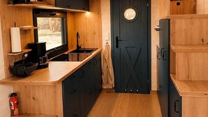 Eine kompakte Küche mit integriertem Fernseher, Holzschränken und einer dunklen Tür.