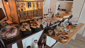 A breakfast buffet with various pastries, bread, and beverages.