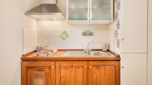 A kitchen with wooden cabinets, a stainless steel sink, and a range hood. - Sottovoce – Intimate vacation home in LericiIn the heart of Lerici, just steps from the sea and immersed in the tranquility of the village, Sottovoce is a small oasis of peace designed for those seeking a private and comfortable stay.This welcoming (Lerici)