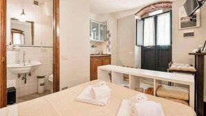 A hotel room with a bed, a desk, a sink, and a mirror. - Sottovoce – Intimate vacation home in LericiIn the heart of Lerici, just steps from the sea and immersed in the tranquility of the village, Sottovoce is a small oasis of peace designed for those seeking a private and comfortable stay.This welcoming (Lerici)