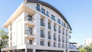 Ένα πολυώροφο ξενοδοχείο με μπαλκόνια, καμπυλωτή στέγη και επίπεδη πρόσοψη.
