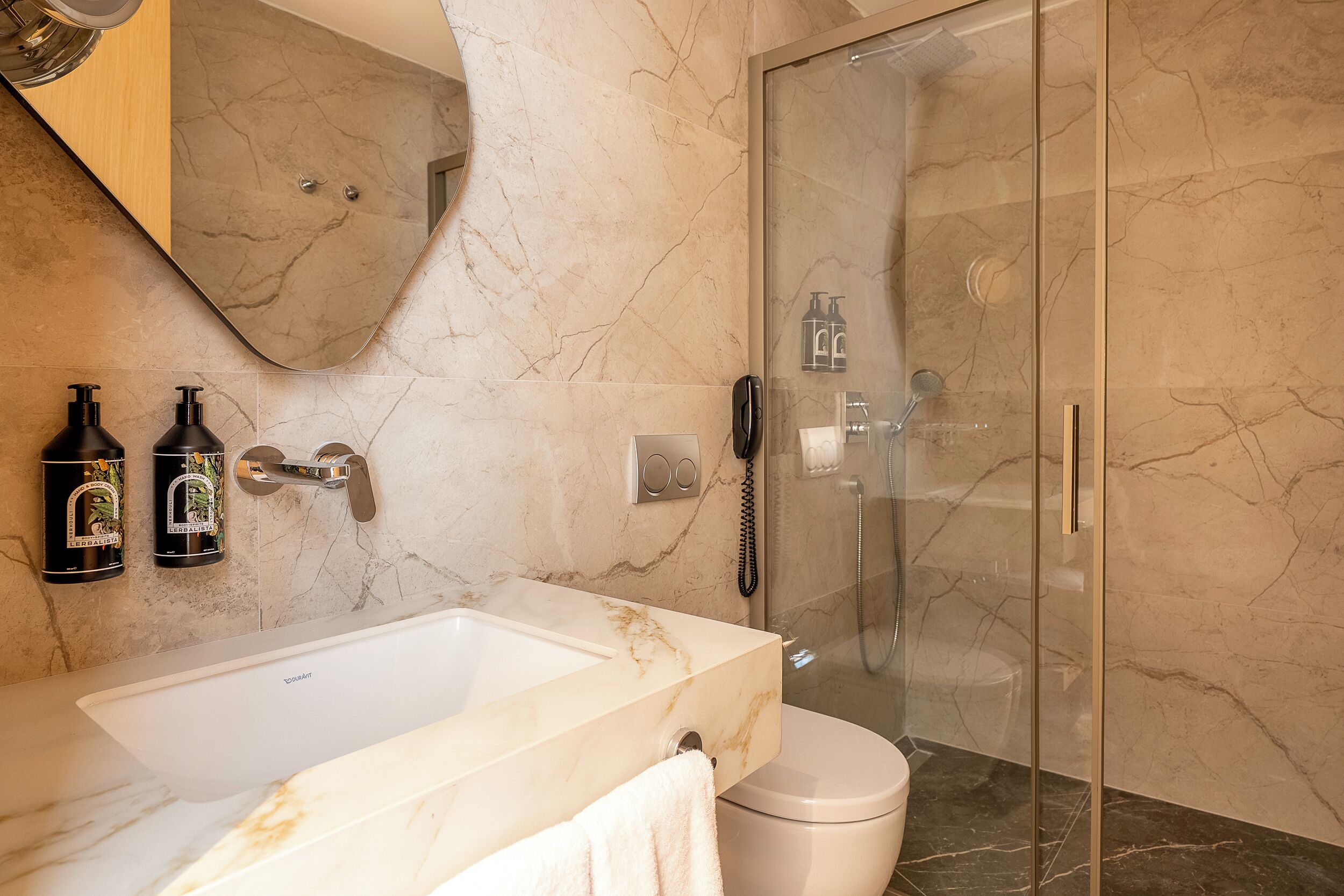 A bathroom with a marble sink, toilet, and glass-enclosed shower.