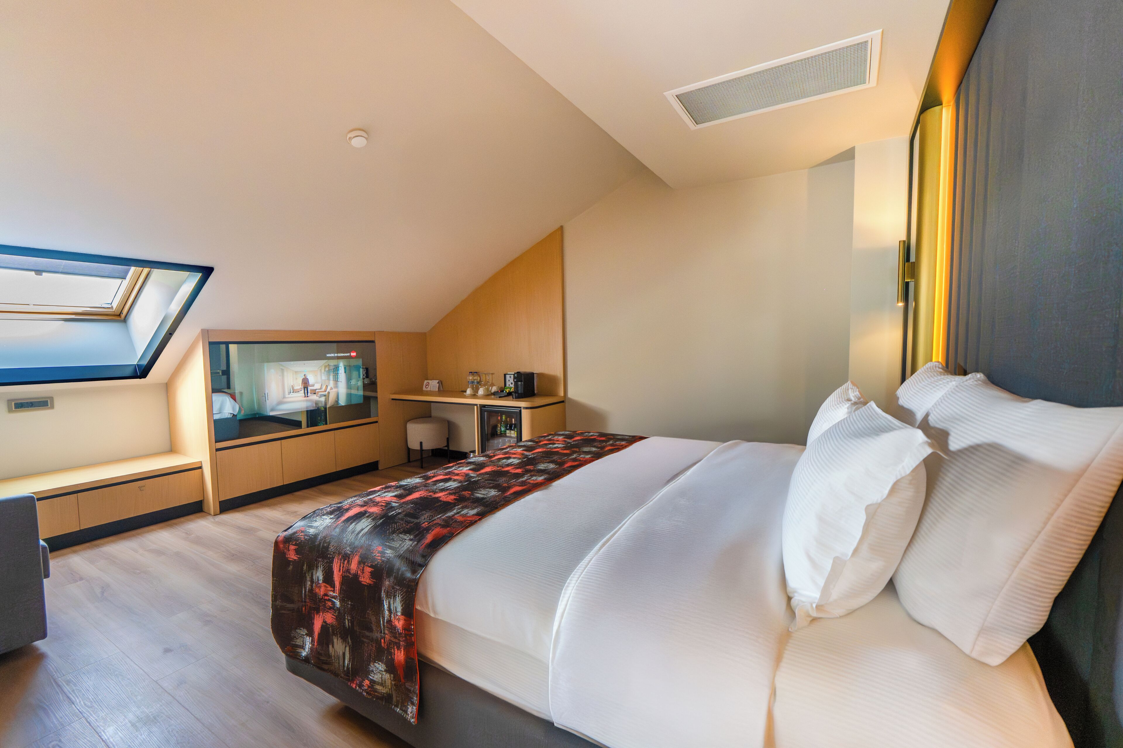 Une chambre d’hôtel moderne équipée d’un grand lit, d’un bureau, d’une chaise et d’une lucarne.