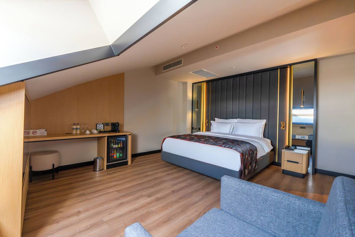 Et moderne hotelværelse med seng, skrivebord, stol, lille bord og spejl.