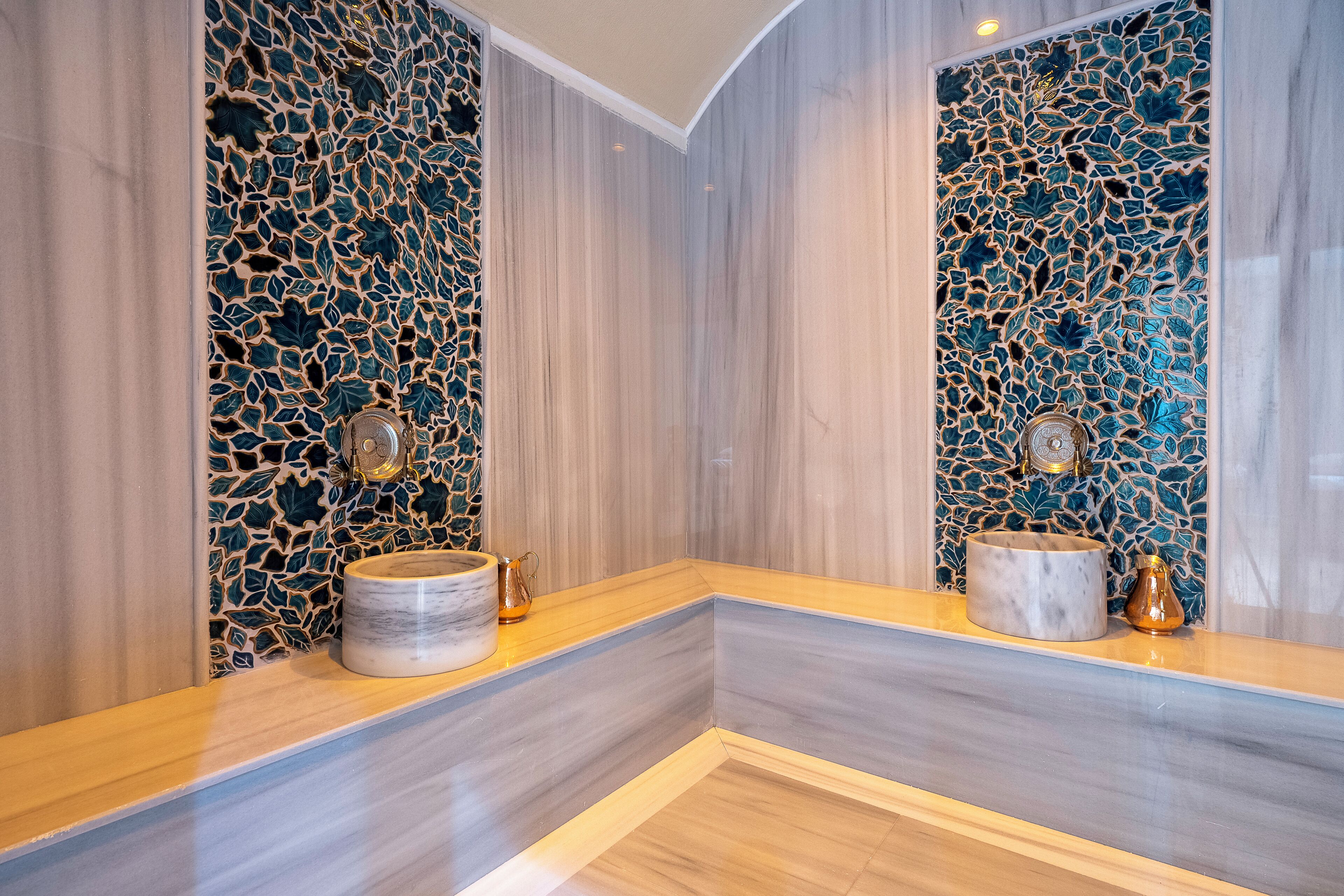 A bathroom with a marble vanity, a decorative mosaic wall, and a mirror.