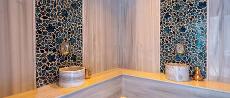A bathroom with a marble vanity, a decorative mosaic wall, and a mirror.