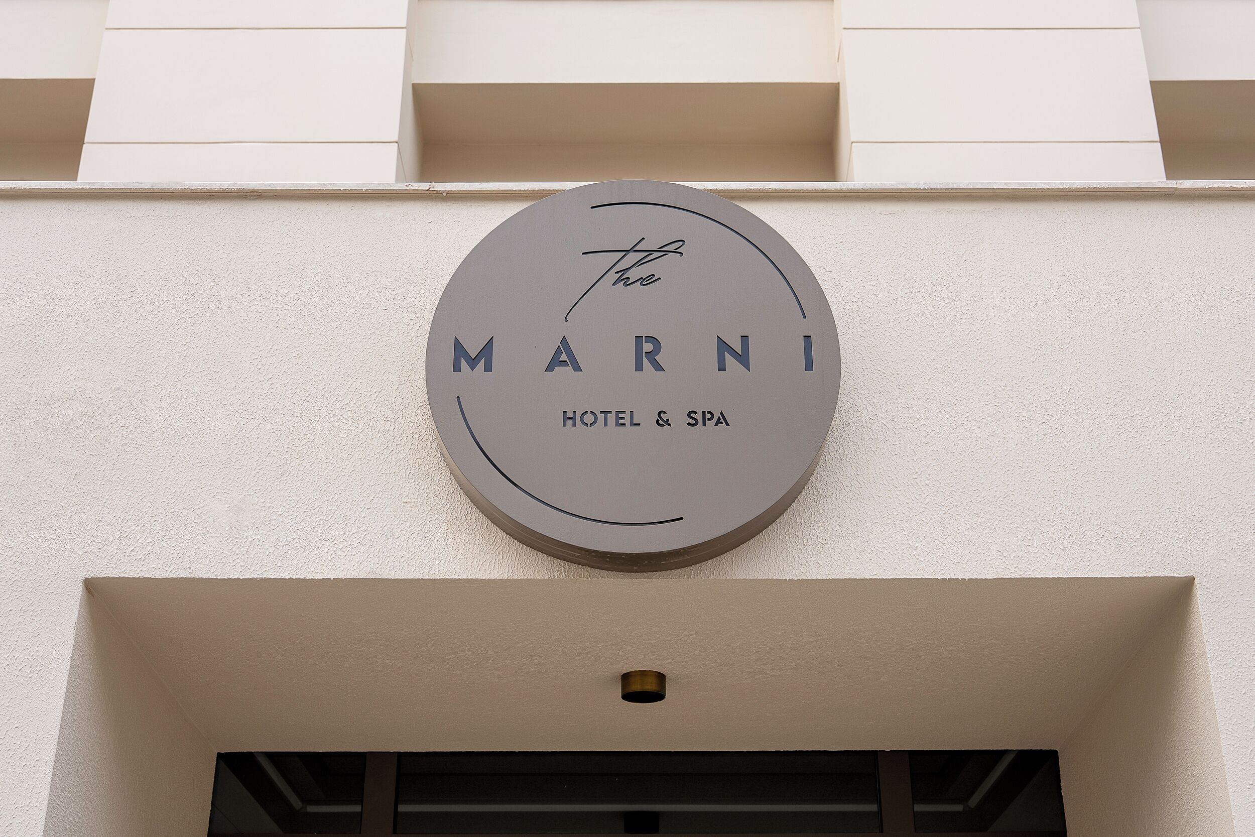 A circular sign with the words 'MARNI HOTEL & SPA' on a building facade.