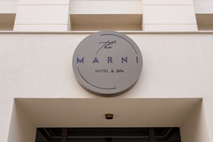 A circular sign with the words 'MARNI HOTEL & SPA' on a building facade.