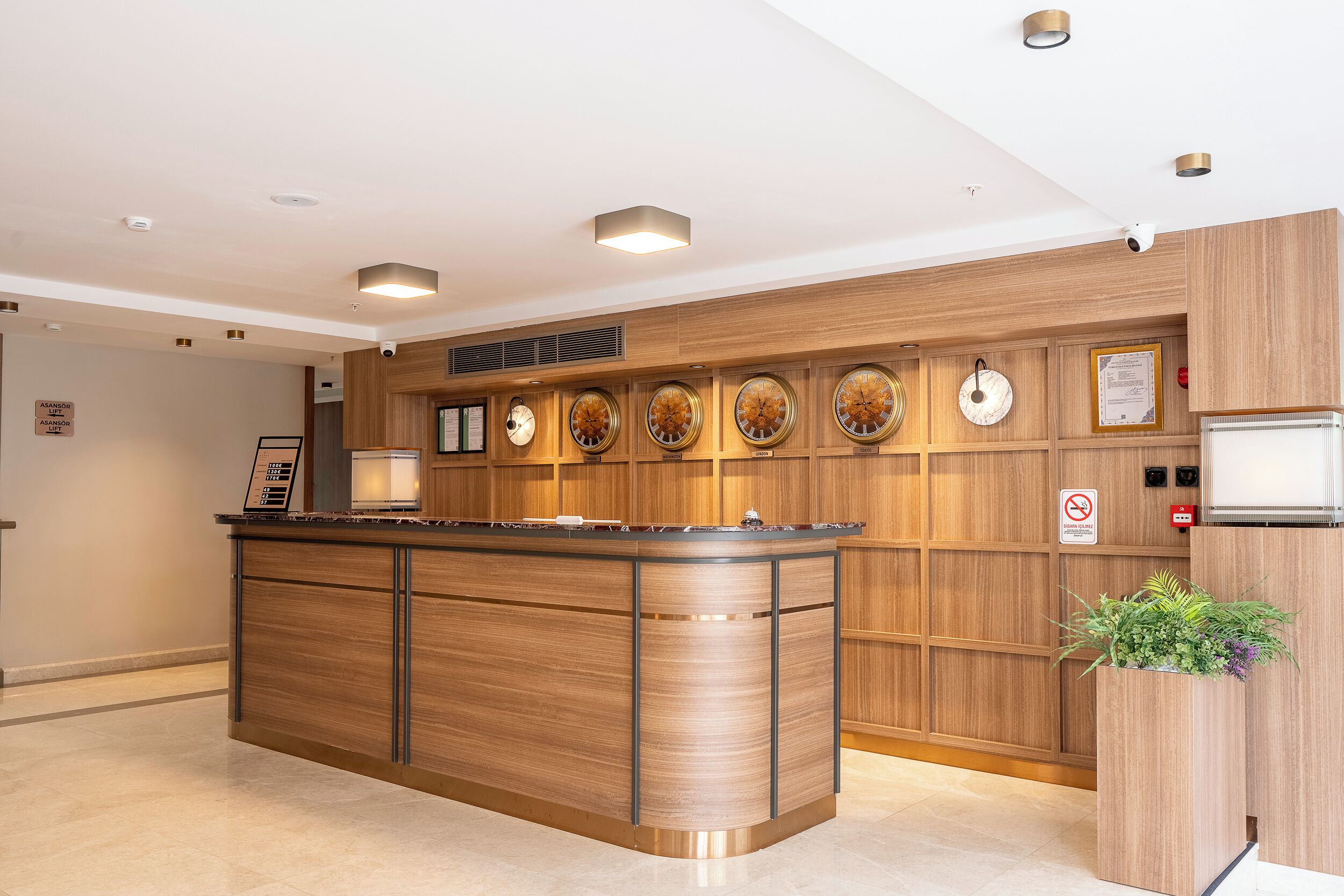 A modern kitchen with a central island, wooden cabinetry, and a series of wall-mounted clocks.