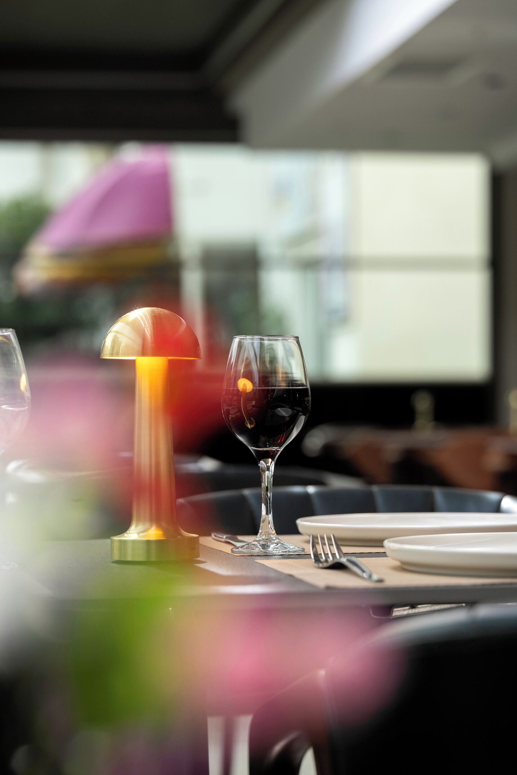 A dining table with a wine glass and a lamp.