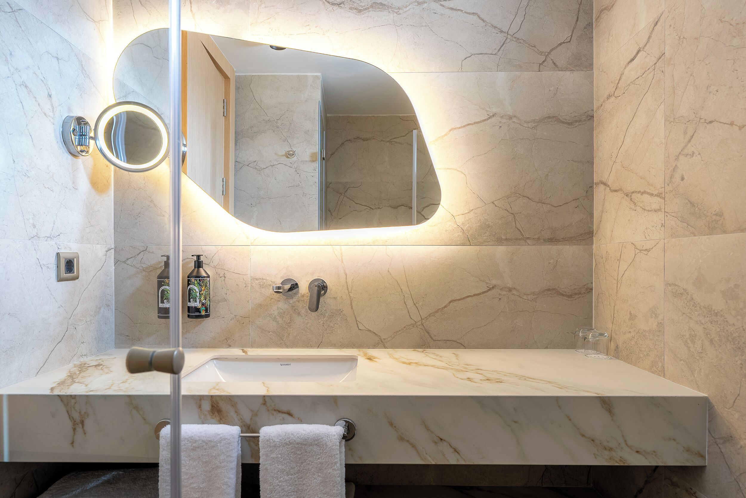A bathroom with a marble sink, a large mirror, and a towel rack.