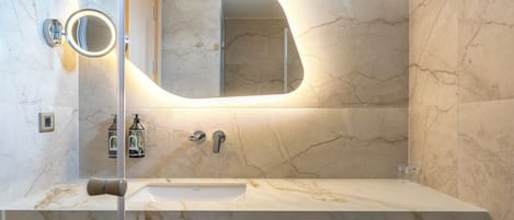 A bathroom with a marble sink, a large mirror, and a towel rack.
