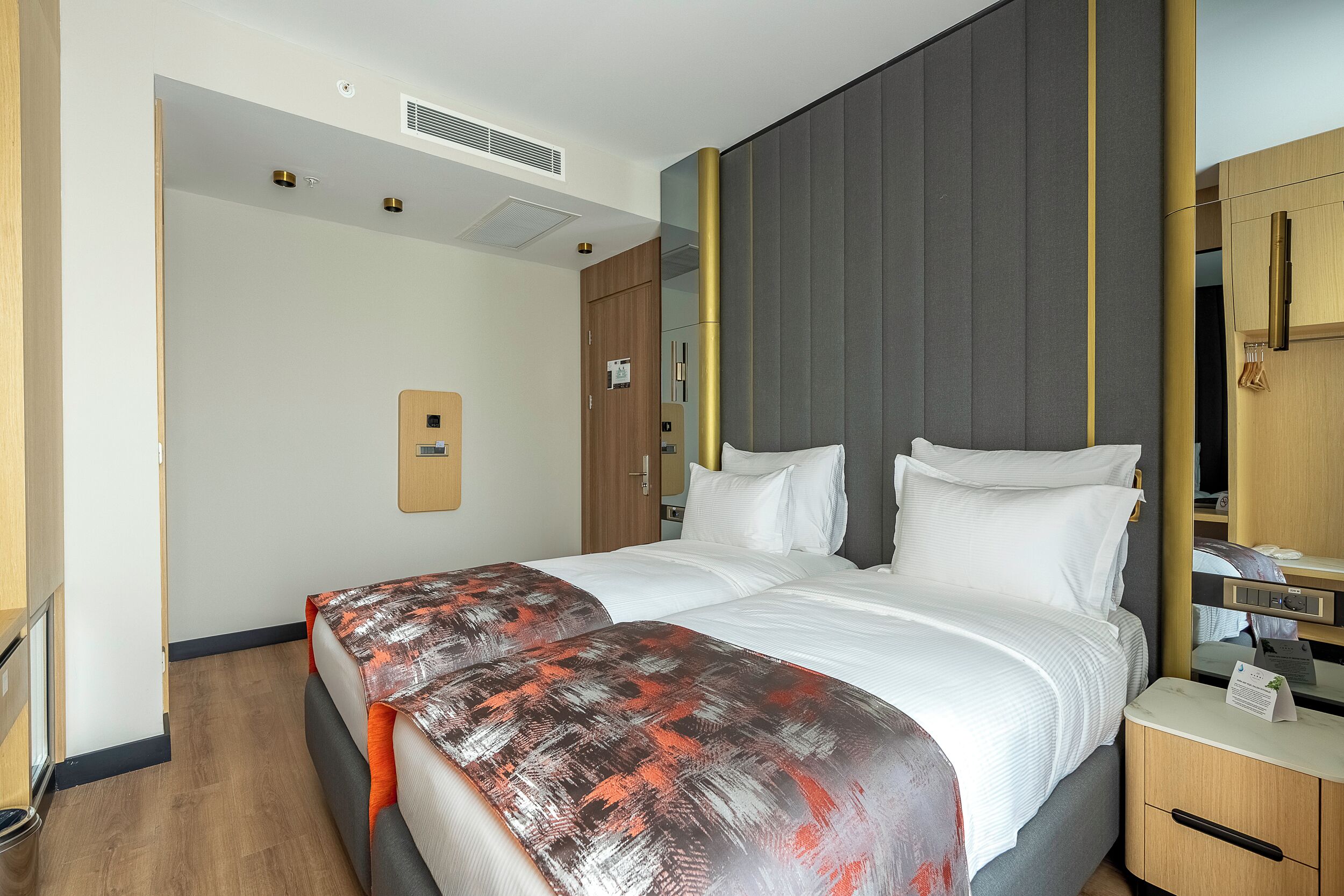 A hotel room with a bed, bedside table, and a wardrobe.