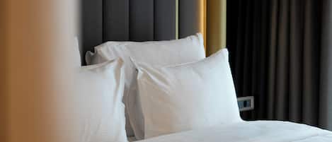 Una cama bien hecha con sábanas blancas, un cabecero oscuro y un panel de control en la pared.