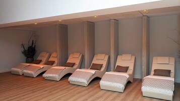 A room with six reclining chairs, each with a pillow and a blanket, arranged in a row.