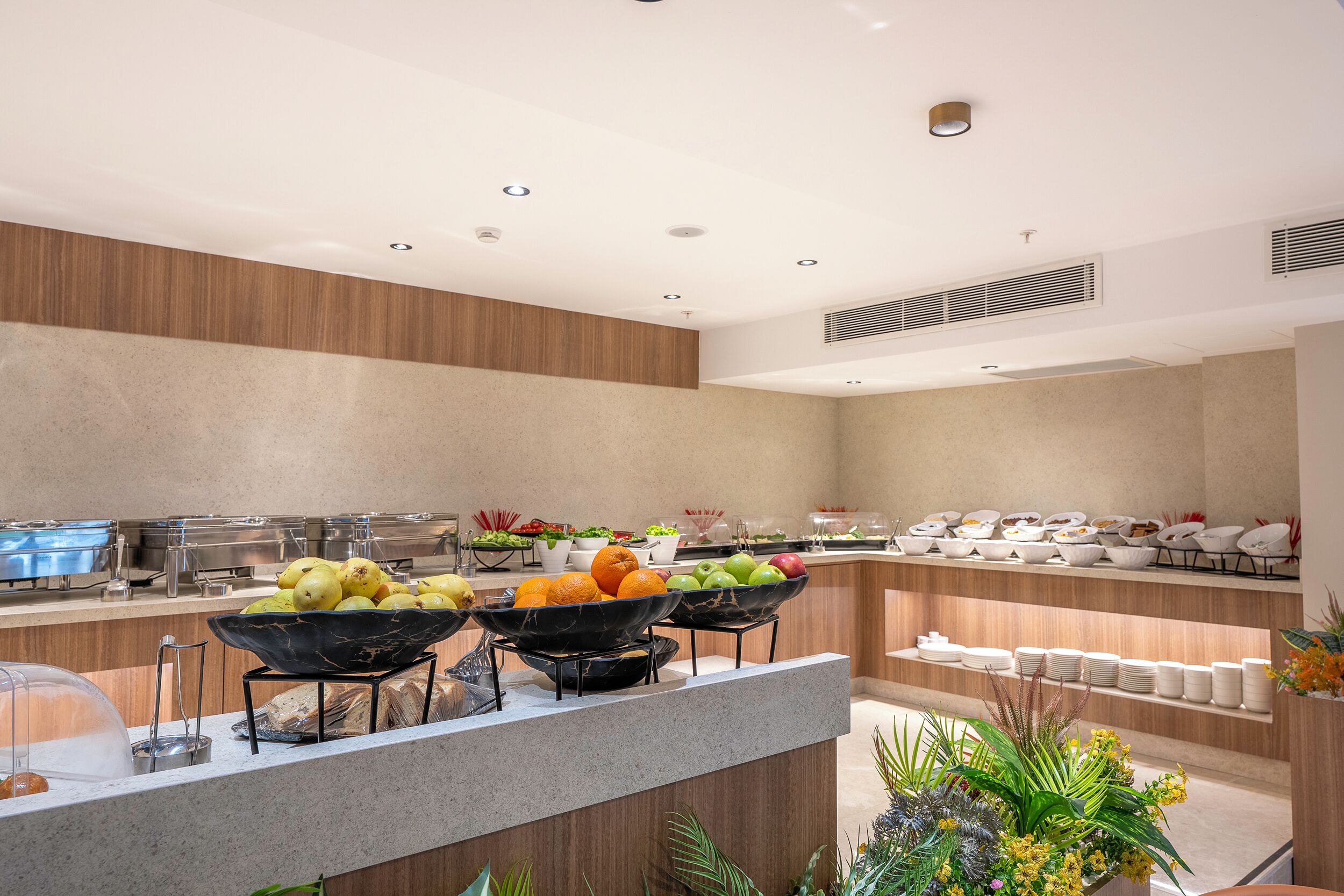 A buffet with various fruits and vegetables, a coffee station, and a variety of dishes on shelves.