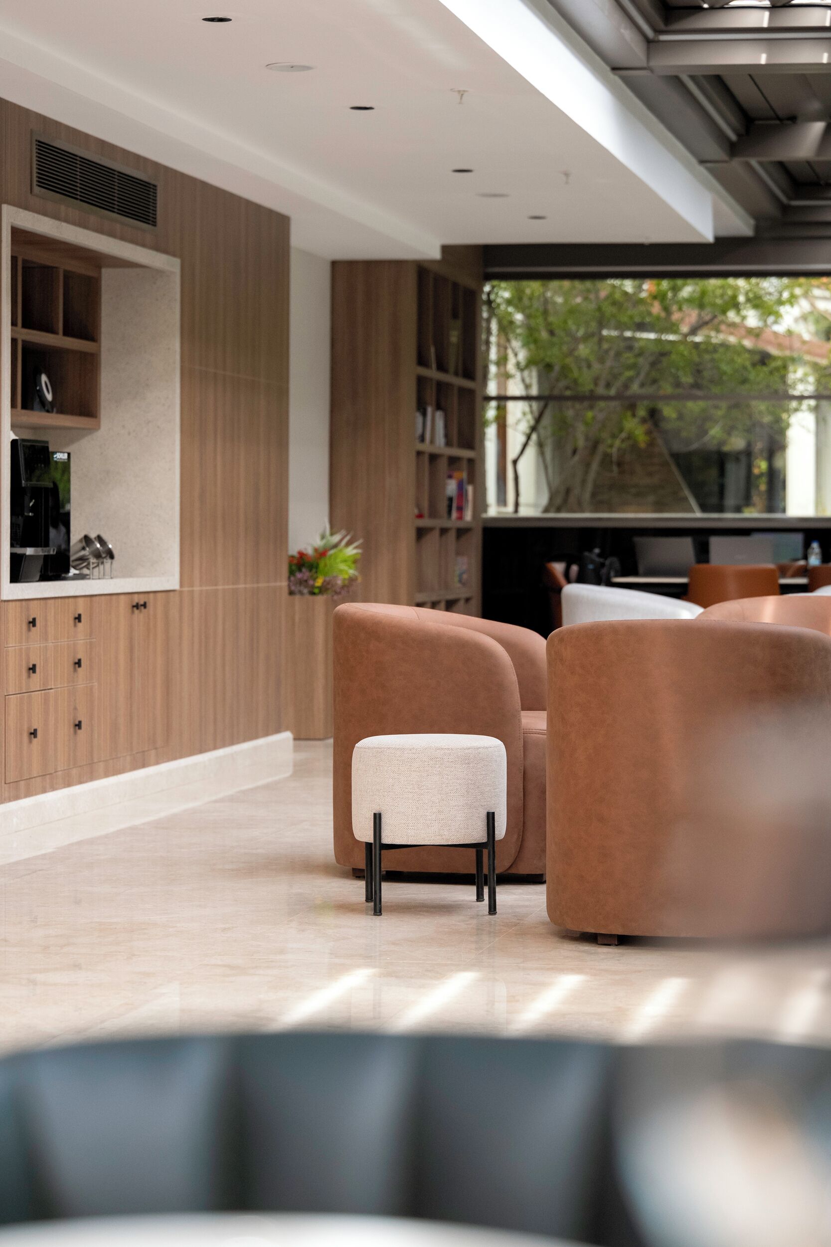 Un espacio moderno con sala, sofá, cafetera y estantería.