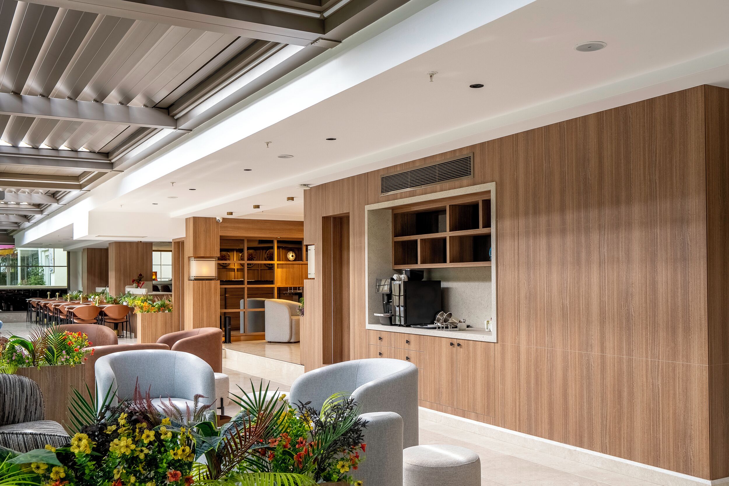 A modern hotel lobby with seating areas, a coffee station, and a reception desk.