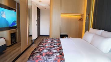 Een hotelkamer met een bed, een televisie, een nachtkastje en een kledingkast.