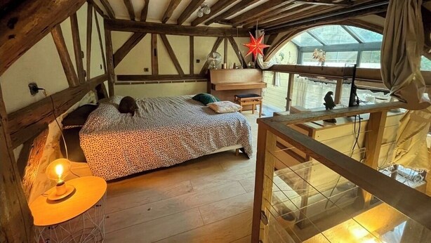 Une chambre mansardée chaleureuse, avec un lit, une petite table et une fenêtre donnant sur la cour.
