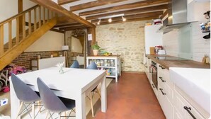 Une cuisine rustique avec des poutres apparentes, un mur en pierre et un plan de travail blanc.