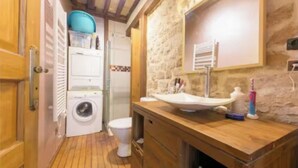 Une petite salle de bain équipée d’un lave-linge, de toilettes et d’un lavabo avec des articles de toilette.