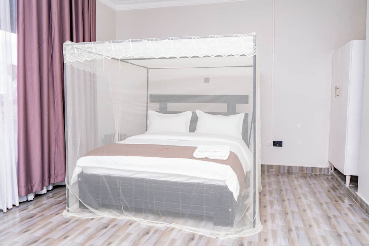 Una cama con dosel, una mesita de noche y un termostato fijado a la pared.