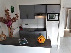 Eine moderne Küche mit grauen Schränken, einem Edelstahl-Kühlschrank und einer Obstschale auf der Arbeitsfläche.