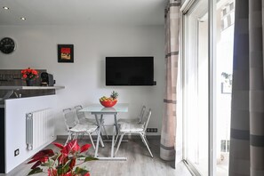 A modern kitchen with a dining area, a flat-screen TV, and a large window. - Apartment 'Le Panorama' with Sea View, Balcony, Wi-Fi and Parking (Cassis)