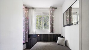 A bedroom with a bed, window, curtains, and a mirror. - Apartment 'Le Panorama' with Sea View, Balcony, Wi-Fi and Parking (Cassis)
