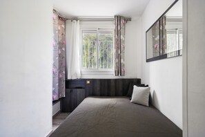 A bedroom with a bed, window, curtains, and a mirror. - Apartment 'Le Panorama' with Sea View, Balcony, Wi-Fi and Parking (Cassis)