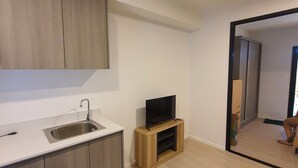 Een moderne keuken met een ingebouwd spoelbakje, een houten kast en een flatscreen televisie op een houten standaard.