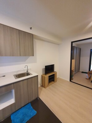 Eine moderne Küche mit integriertem Spülbecken, einem Holzkasten und einem Flachbildfernseher auf einem Holzständer.