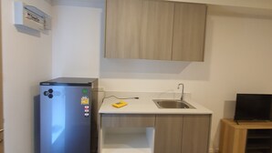 Een praktische keuken met een koelkast, een spoelbak en een klein houten kastje.