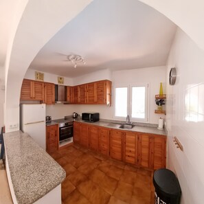 Une cuisine avec des meubles de rangement en bois, un four encastré, un four à micro-ondes et un évier.