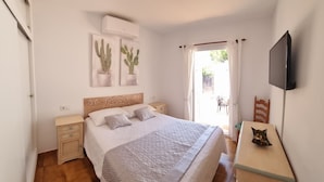 Un dormitorio con cama, mesitas de noche, un televisor y dos cuadros de cactus.