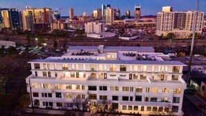 Een hotel met meerdere verdiepingen, een plat dak en een gelijkmatig raamontwerp, omgeven door een stadsgezicht in de schemering.