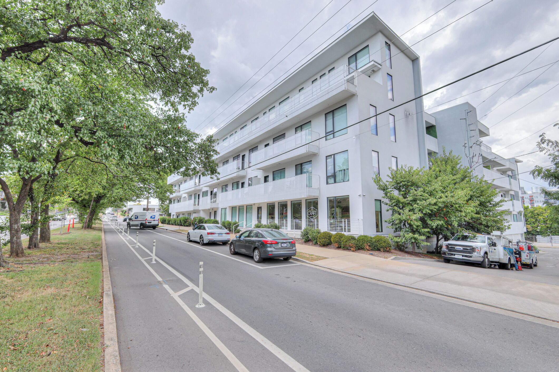 Monikerroksinen rakennus, jossa on moderni arkkitehtoninen ilme. Rakennuksen yhteydessä on useita parkkipaikkoja, ja niissä on useita autoja sekä huoltoauto.
