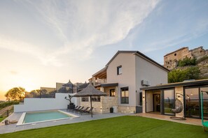 A modern house with a swimming pool, outdoor seating, and a view of a historic building. - Villa Aurana Zadarvillas (Pakostane)