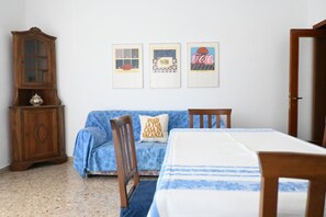 Ein Zimmer mit einem Bett, einem Holzschrank, einem blauen Sofa und drei gerahmten Bildern an der Wand.
