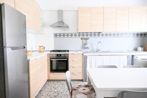 Cozinha compacta com geladeira, forno, fogão e pia.