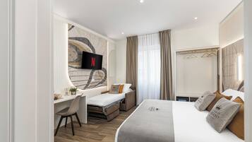 A hotel room with a bed, a desk, a TV, and a large mirror.