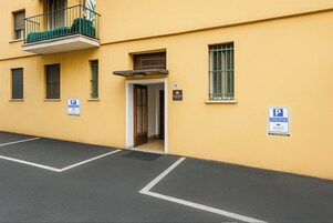 Un edificio giallo con un balcone, una porta e due segnali di divieto di sosta.