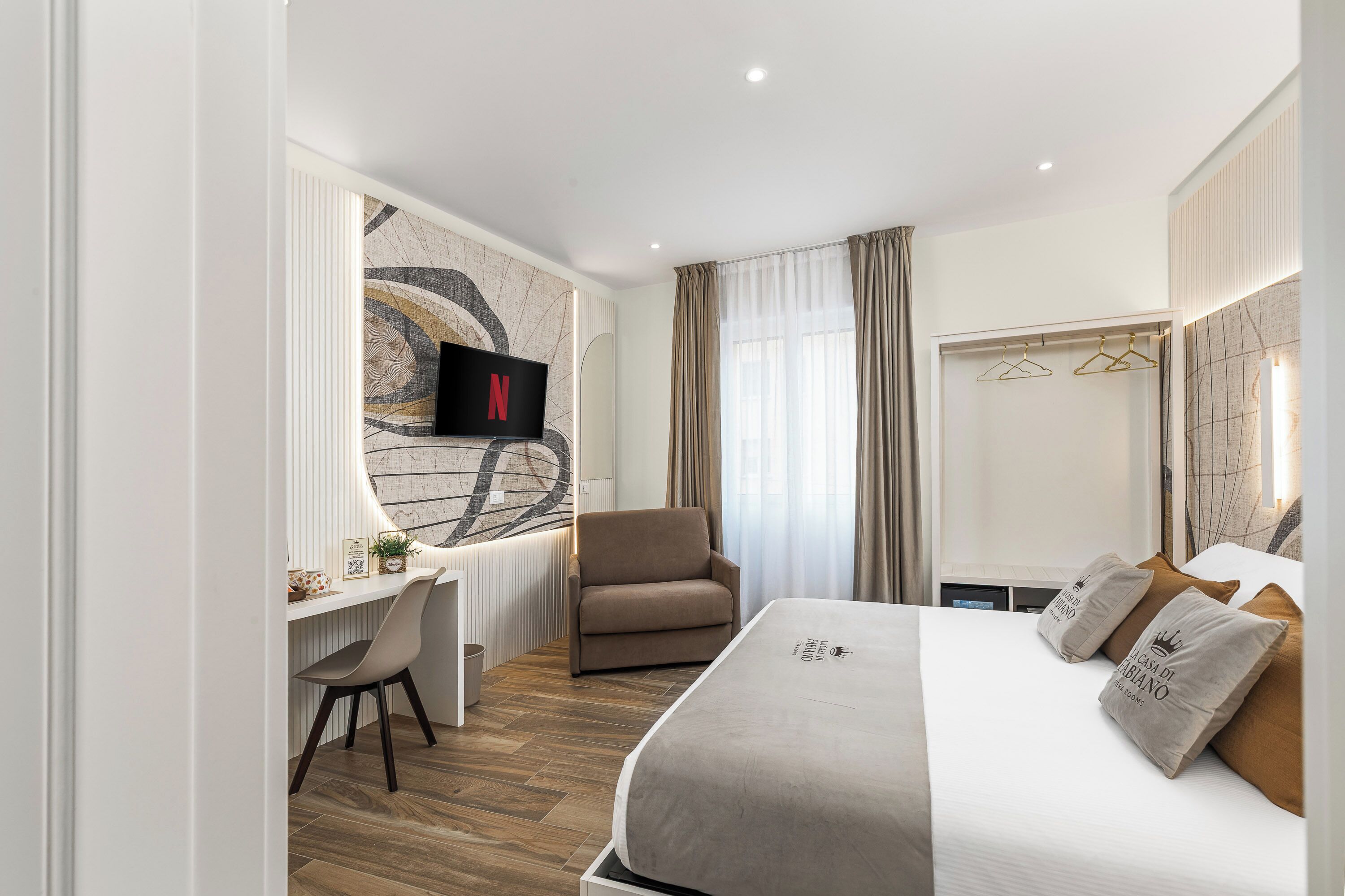 Une chambre d’hôtel moderne équipée d’un lit, d’un bureau, d’une chaise, d’une télévision et d’un grand miroir.