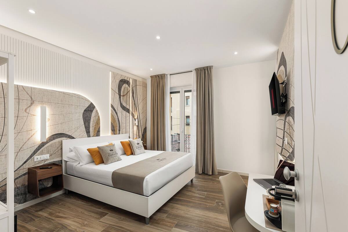 Une chambre à coucher moderne avec un lit, une table de chevet et un bureau avec un ordinateur portable.