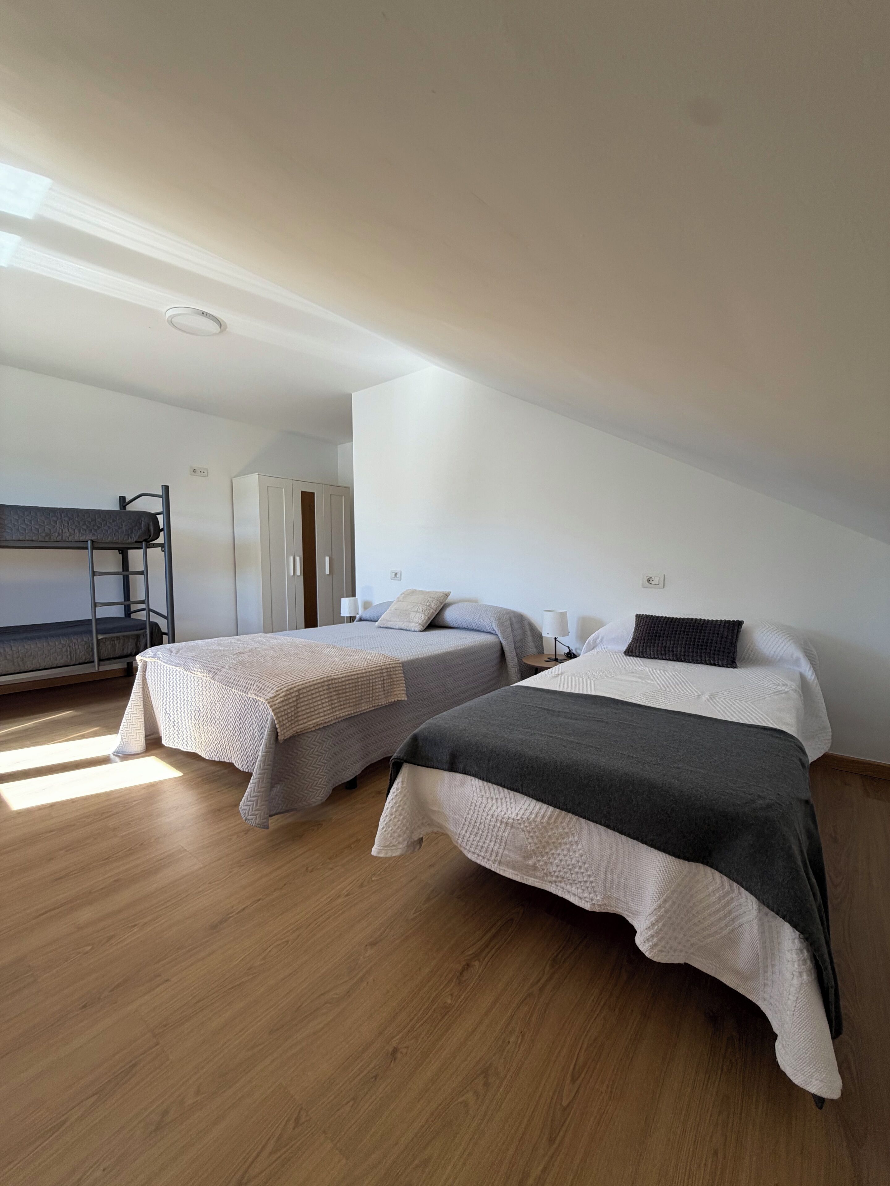Una habitación con dos camas, incluyendo una litera, y un armario.