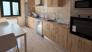 Une cuisine moderne avec des meubles en bois, des appareils électroménagers en acier inoxydable, un lave-vaisselle et une fenêtre donnant sur un beau paysage.