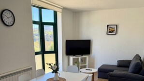 Un salon moderne comprenant une table à manger, des chaises, un canapé, un téléviseur et une fenêtre donnant sur un beau paysage.